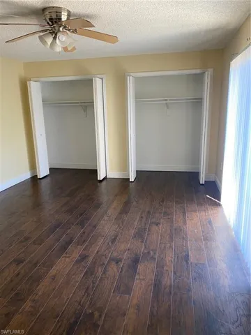 Bedroom 1 with multiple closets, laminate floors, and a ceiling fan