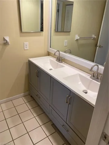 Bathroom with double vanity and light tile  floors.