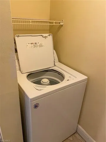 Laundry area in 1st floor bathroom with washer and baseboards.