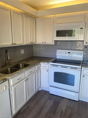 Kitchen featuring range oven, tile backsplash, microwave, and vinyl floors
