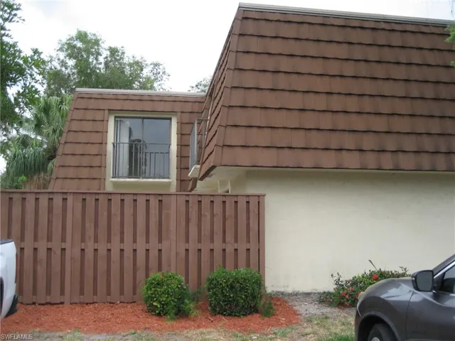 View of side of home featuring mansard roof and stucco siding
