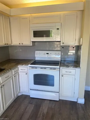Kitchen with white electric range, white cabinets, and vinyl floors