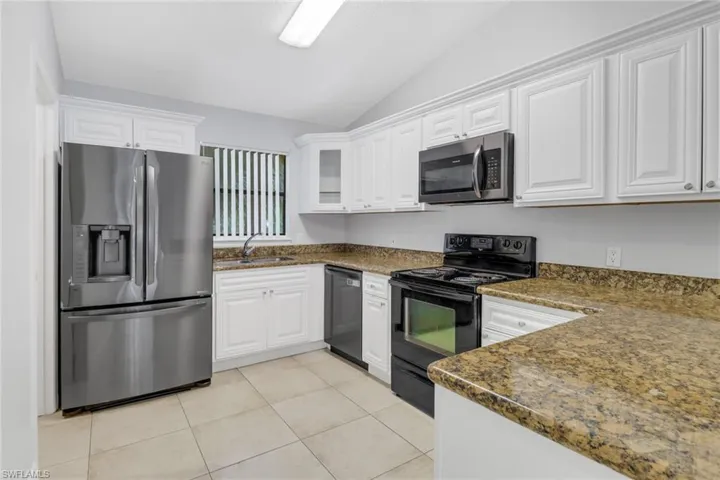 Kitchen featuring lofted ceiling, white cabinetry, sink, and appliances with stainless steel finishes