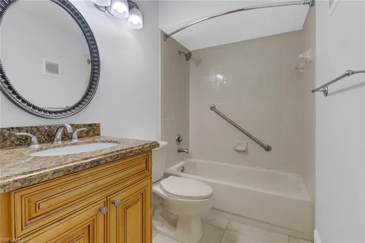 Full bathroom with vanity, tile patterned floors, toilet, and tiled shower / bath