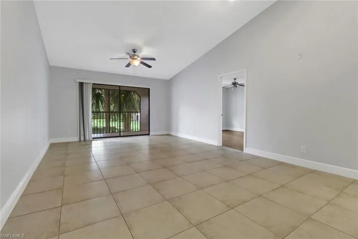 Tiled empty room featuring high vaulted ceiling and ceiling fan