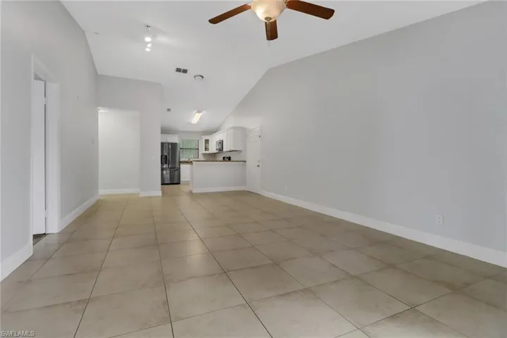 Unfurnished living room featuring light tile patterned flooring, ceiling fan, and vaulted ceiling
