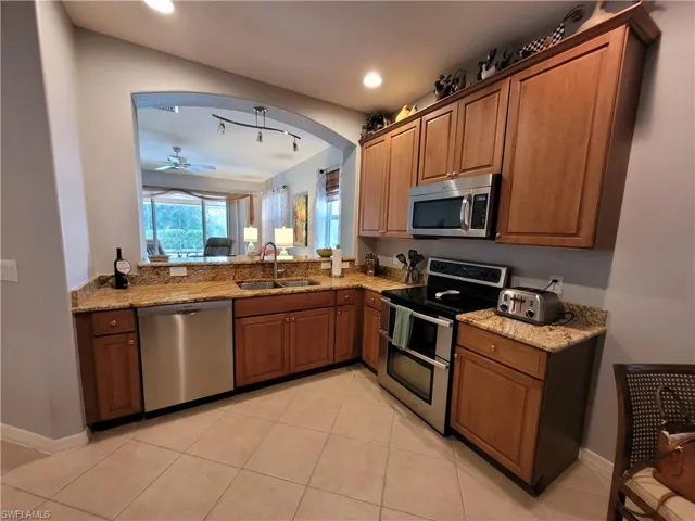 Kitchen with appliances with stainless steel finishes, arched walkways, light tile patterned flooring, recessed lighting, and a textured ceiling
