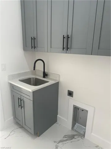 Washroom with sink, electric dryer hookup, and light tile floors