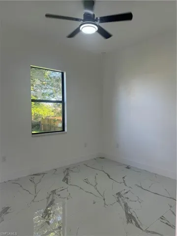 Tiled spare room featuring ceiling fan