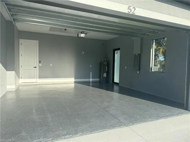 Garage featuring a garage door opener and electric water heater