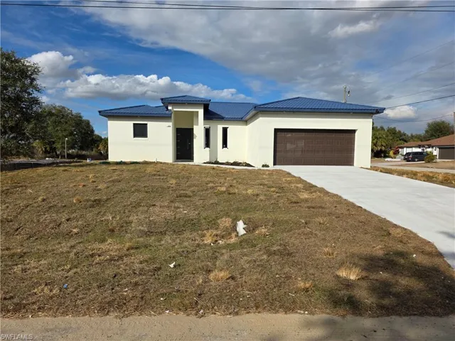 Prairie-style house with driveway, an attached garage, stucco siding, and a front yard