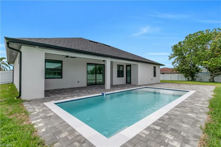 Rear view of property with a fenced backyard, a patio area, a ceiling fan, roof with shingles, and stucco siding