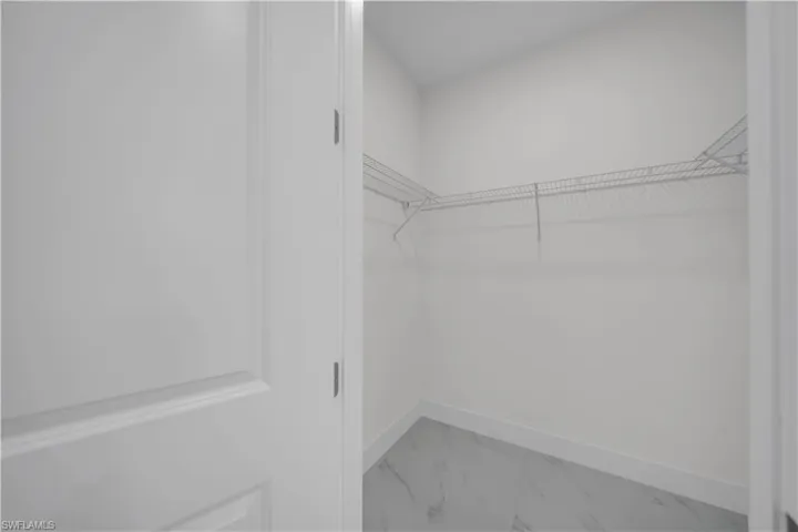 Walk in closet featuring light marble finish flooring