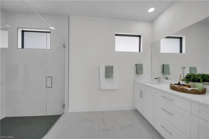 Bathroom featuring a marble finish shower, vanity, and light marble finish floors