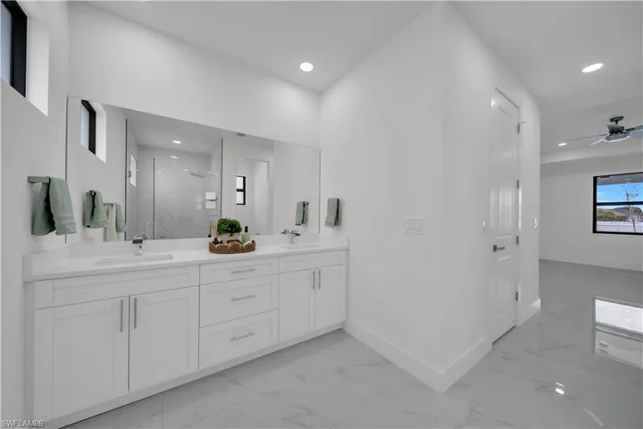 Full bathroom with a marble finish shower, double vanity, recessed lighting, a ceiling fan, and light marble finish flooring