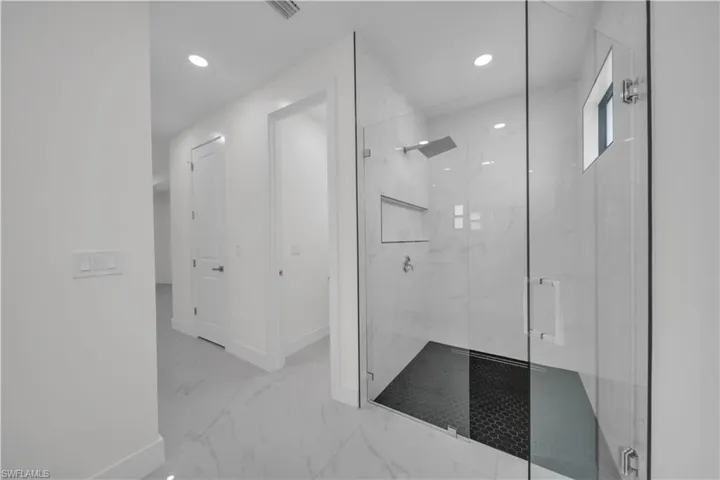 Full bath featuring a marble finish shower, light marble finish flooring, and recessed lighting