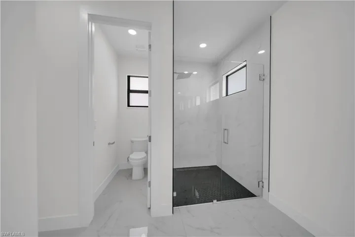 Full bath featuring a marble finish shower, recessed lighting, and light marble finish flooring