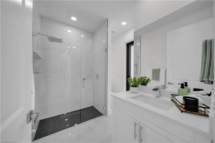 Bathroom featuring vanity, a marble finish shower, and recessed lighting