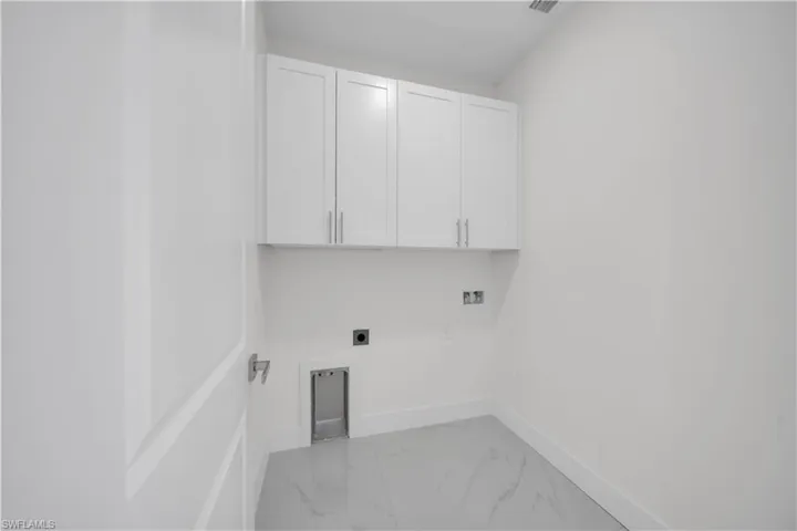 Laundry room with cabinet space, hookup for an electric dryer, and light marble finish flooring