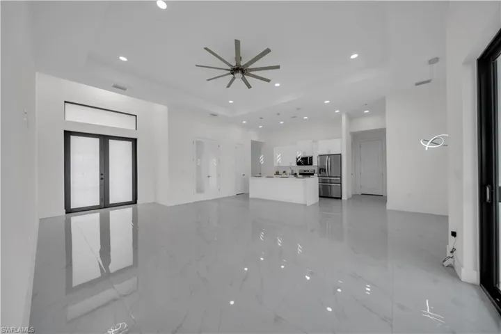 Unfurnished living room featuring a raised ceiling, recessed lighting, french doors, light marble finish floors, and ceiling fan