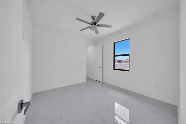 Unfurnished room featuring light marble finish floors and a ceiling fan