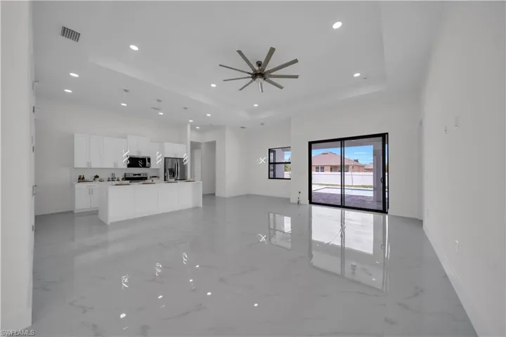 Unfurnished living room featuring a raised ceiling, light marble finish flooring, recessed lighting, and a ceiling fan
