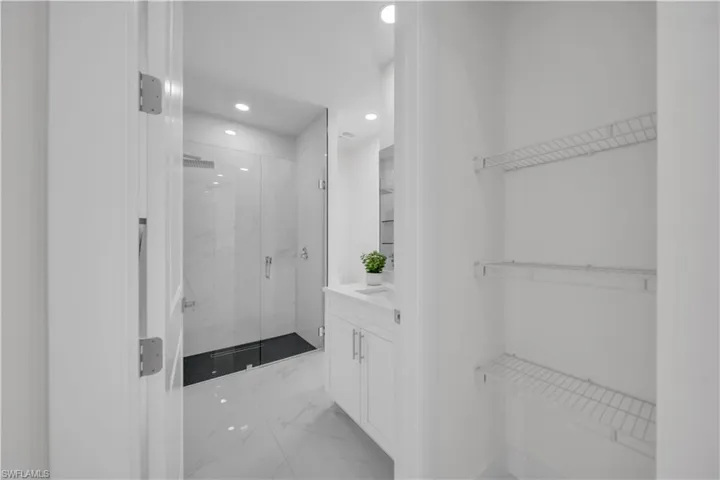 Full bathroom featuring vanity, light marble finish flooring, a marble finish shower, recessed lighting, and a spacious closet