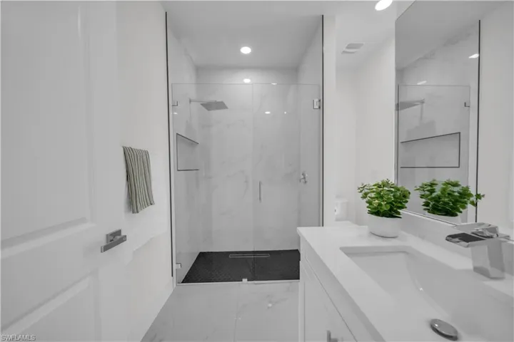 Bathroom with vanity, light marble finish flooring, a marble finish shower, and recessed lighting