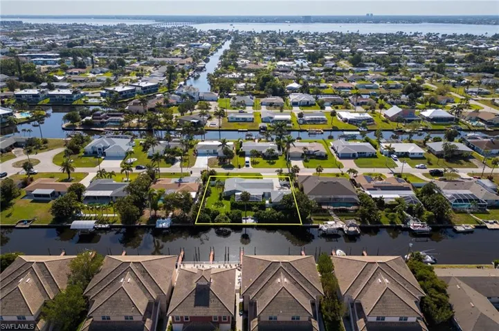 Aerial view of residential area with property boundaries highlighted and a nearby body of water