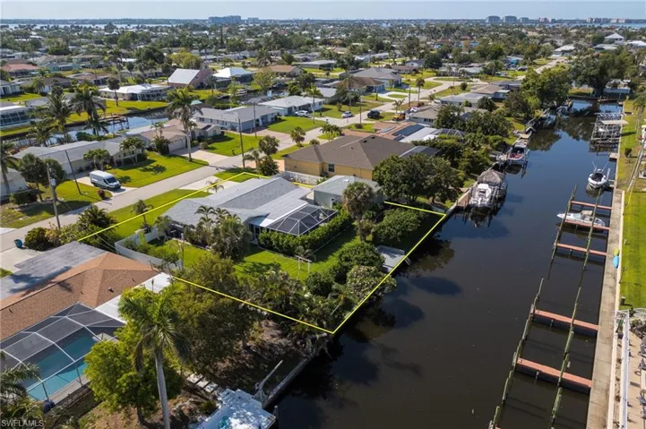 Aerial view of residential area with a large body of water and property parcel outlined