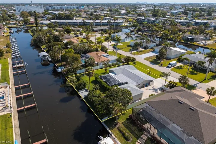 Aerial view of residential area with a nearby body of water and property parcel outlined