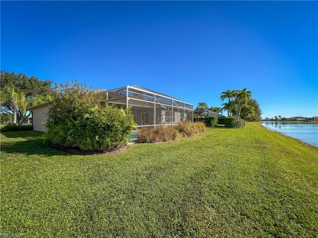 View of green lawn with a sunroom, a lanai, and a water view