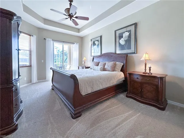 Bedroom with a raised ceiling, access to outside, carpet flooring, and ceiling fan