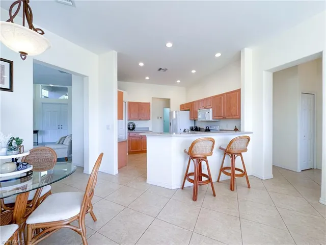 Kitchen with a breakfast bar area, a peninsula, recessed lighting, light countertops, and white appliances