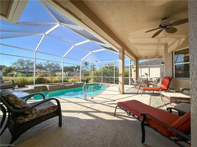 Swimming pool featuring a sunroom, a patio area, glass enclosure, and a jacuzzi
