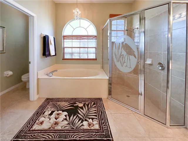 Full bath featuring a bath, a shower stall, light tile patterned floors, and a chandelier