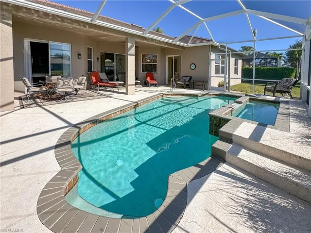 View of swimming pool featuring a patio, glass enclosure, a sunroom, and a pool with connected hot tub