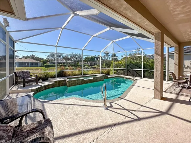 View of swimming pool featuring a sunroom, a patio, glass enclosure, and a pool with connected hot tub