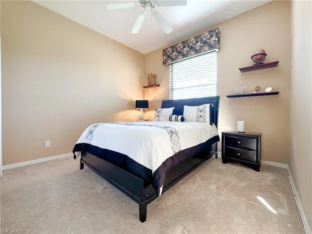 Bedroom with light colored carpet and a ceiling fan