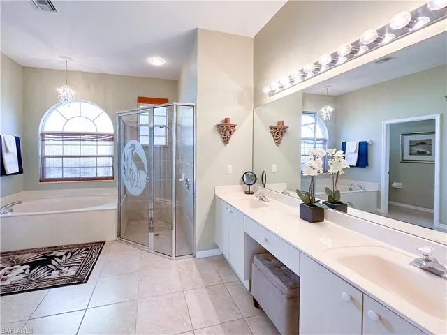 Bathroom featuring a garden tub, double vanity, a chandelier, and healthy amount of natural light