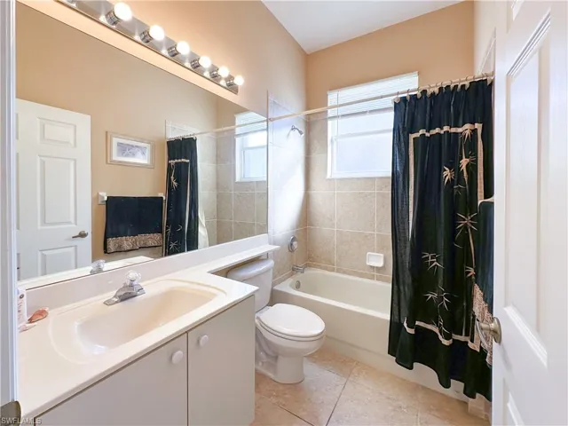 Full bathroom with shower / bath combo with shower curtain, vanity, and light tile patterned flooring