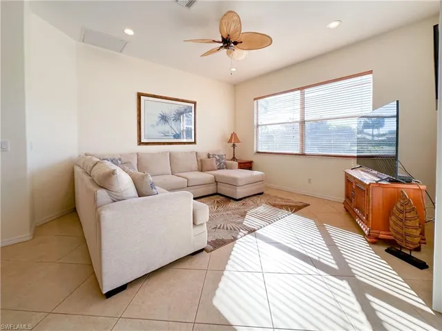Living room with a ceiling fan, light tile patterned flooring, recessed lighting, and attic access