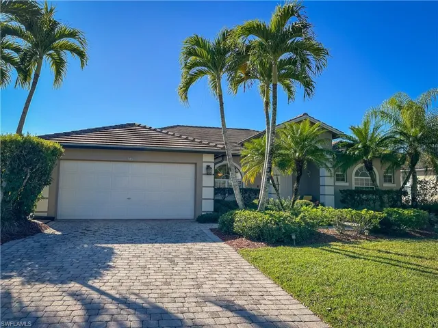 View of front of house featuring decorative driveway, a front lawn, stucco siding, a tile roof, and an attached garage