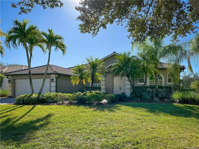 View of front of property featuring a front lawn, a garage, stucco siding, and a tile roof