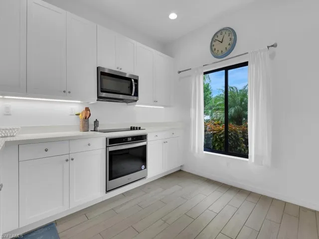 Kitchen featuring stainless steel appliances, white cabinetry, wood tiled floors, and recessed lighting