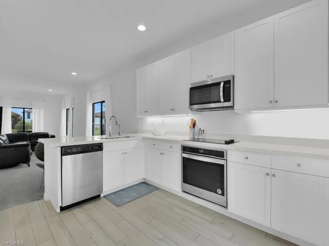 Kitchen with stainless steel appliances, white cabinetry, open floor plan, recessed lighting, and a peninsula