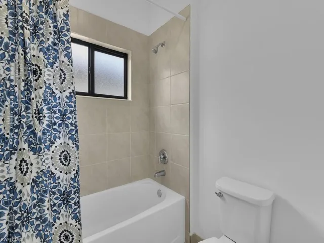 Bathroom with toilet and shower / bath combination with curtain