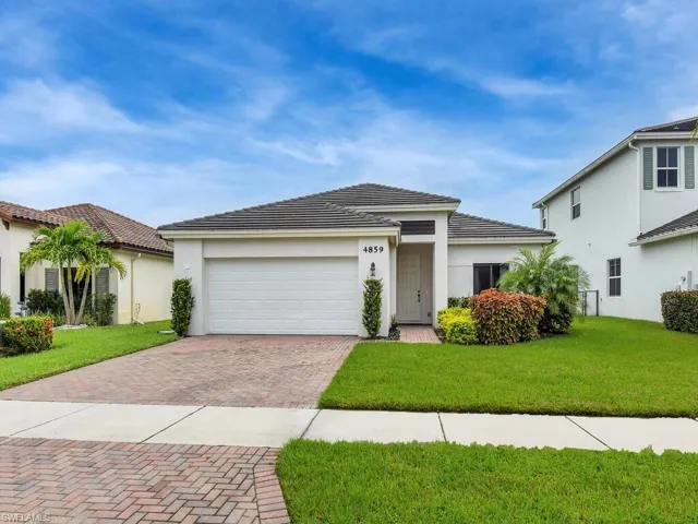 View of front facade featuring a garage, decorative driveway, a front lawn, stucco siding, and a tiled roof