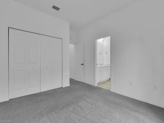 Unfurnished bedroom featuring light carpet, a closet, and connected bathroom