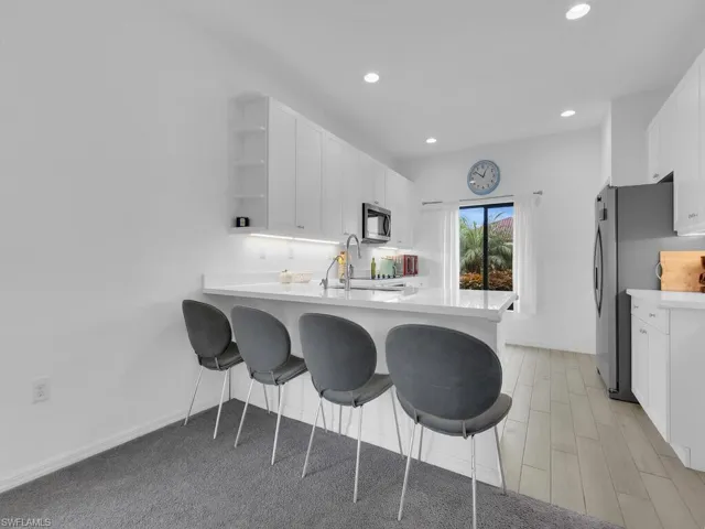 Kitchen with white cabinets, open shelves, a kitchen breakfast bar, stainless steel appliances, and a peninsula